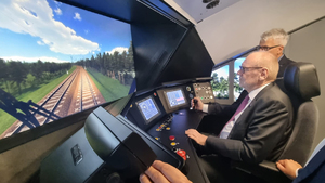 Josef Doppelbauer, Dyrektor Wykonawczy Agencji Kolejowej Unii Europejskiej siedzący w symulatorze jazdy lokomotywą. Na przeciw wyświetlana jest symulacja trasy kolejowej na monitorze